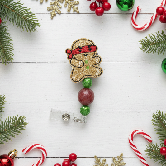 Christmas-themed badge holder with gingerbread design surrounded by festive decorations on a white wooden surface.