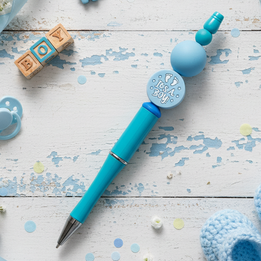 A pink beaded pen with a circular decorative element featuring a floral-like design on the cap, presented against a pink background.