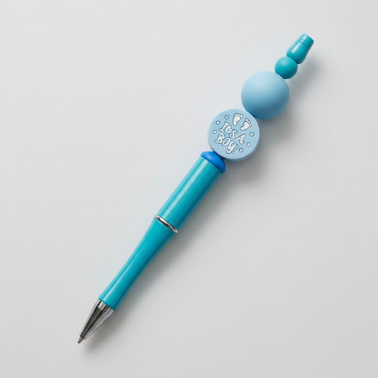 A pink beaded pen with a circular decorative element featuring a floral-like design on the cap, presented against a pink background.