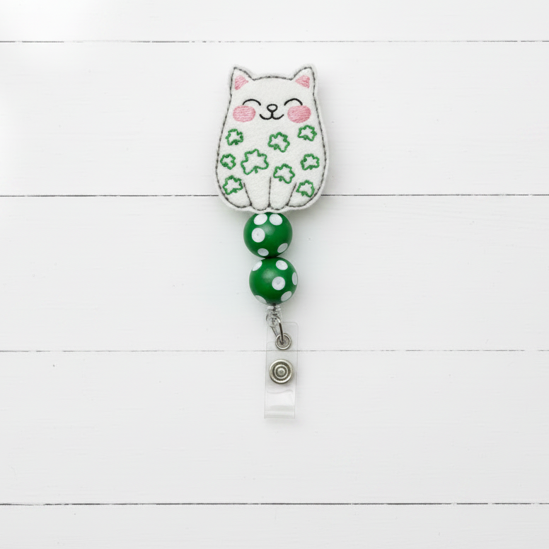Cat-shaped badge holder with green polka dot ribbon on a white background