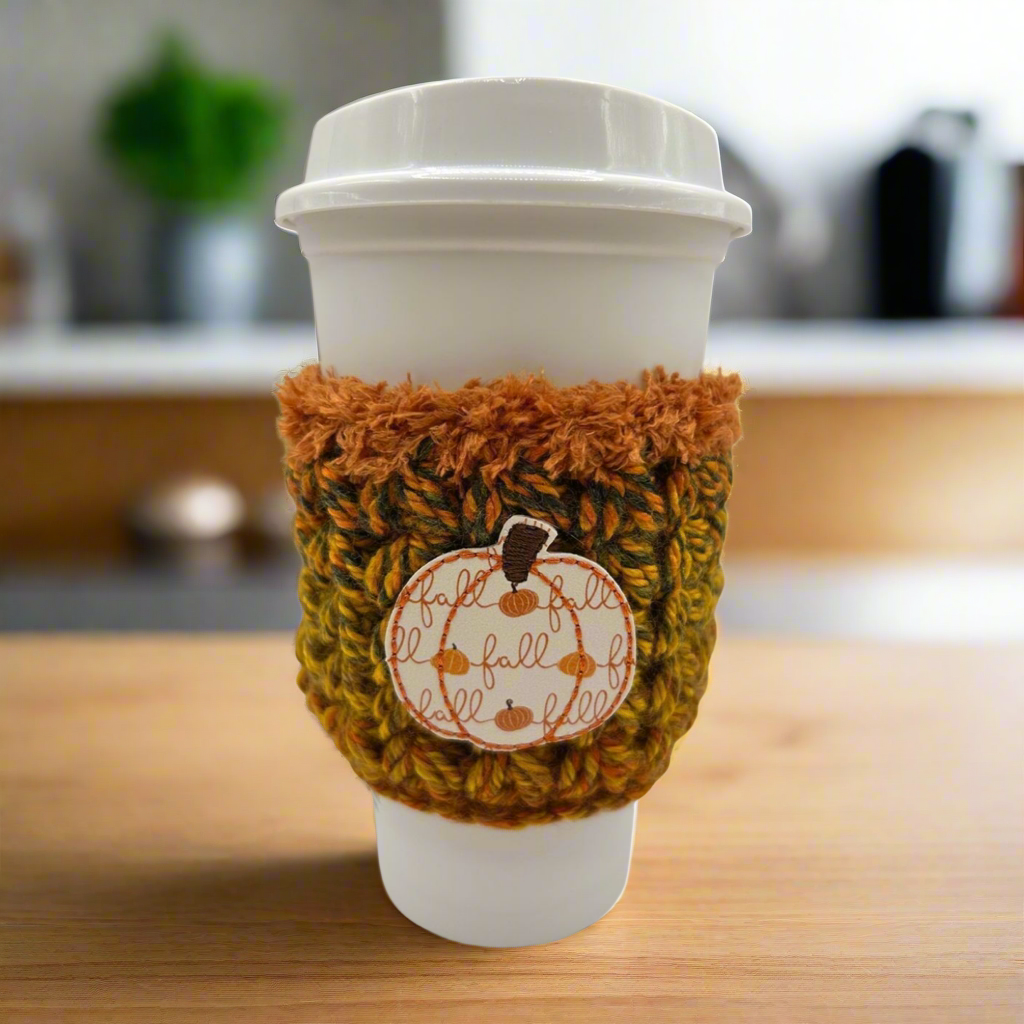 Coffee cup with a cozy fall-themed sleeve on a wooden surface.