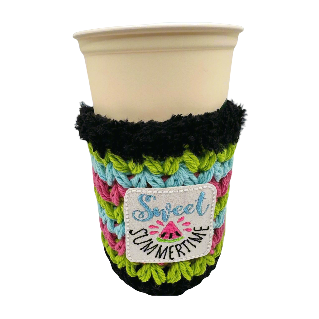A crocheted multicolored drink cozy with the text 'Sweet Summertime' displayed on a cup.