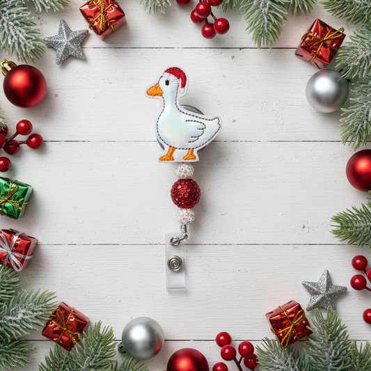 Decorative badge holder with a goose design surrounded by Christmas ornaments on a wooden surface.