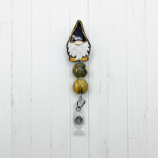 A black and gold gnome beaded badge reel with a retractable cord and rotating clip.