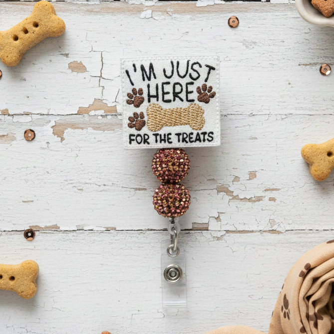 Badge holder with 'I'm just here for the treats' text and paw prints on a white background