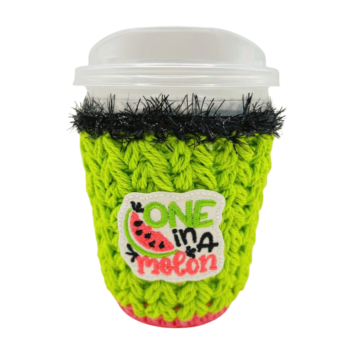 Green knitted coffee cup cozy with 'One in a Melon' patch on a white background