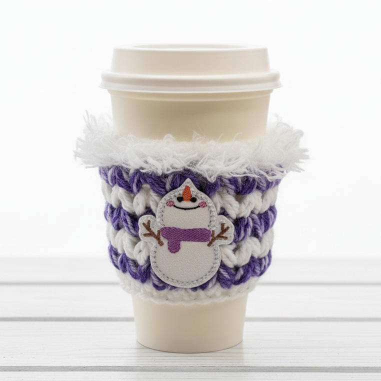 A coffee cozy sleeve with a snowman design, primarily in blue and gray tones, wrapped around a coffee cup.