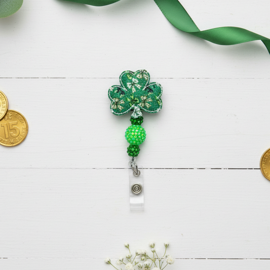 Green shamrock-shaped badge holder with beads on a white background