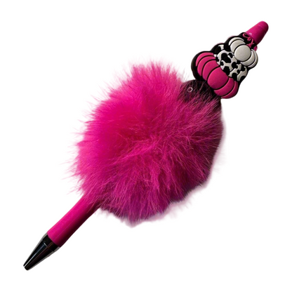 A pink pen with a decorative pumpkin charm and beads, attached to a fluffy pink top.