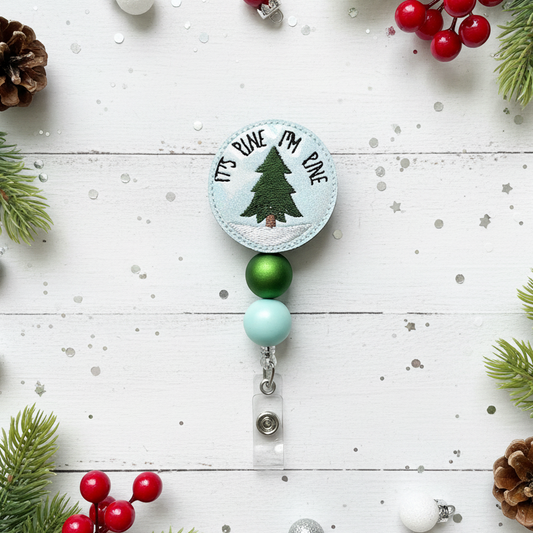 Christmas-themed badge holder with tree design on a white wooden surface with festive decorations.