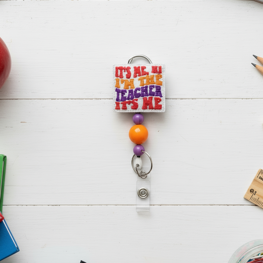 Colorful keychain with text 'It's me, hi I'm the teacher it's me' on a white background