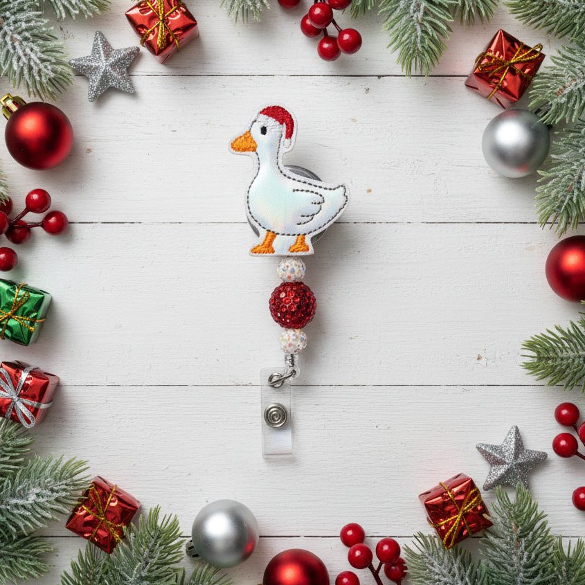Decorative badge holder with a goose design surrounded by Christmas ornaments on a wooden surface.