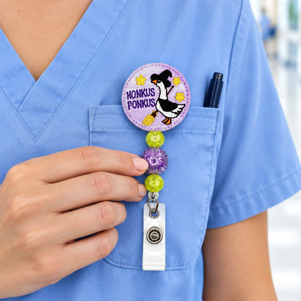 A close-up of a person in light blue medical scrubs wearing a round pin that says 'Honolulu Ponki!' and holding a retractable badge reel with a matching pin.