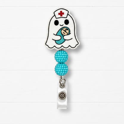 A ghost-shaped nurse badge reel with a cute embroidered baby design, featuring two turquoise beaded loops and a silver retractable clip, set against a white wood plank background.