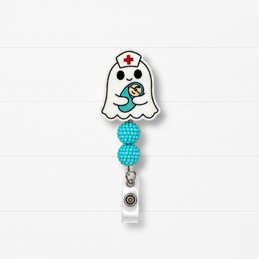 A ghost-shaped nurse badge reel with a cute embroidered baby design, featuring two turquoise beaded loops and a silver retractable clip, set against a white wood plank background.
