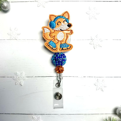 Fox-shaped badge holder with blue accents on a white wooden background