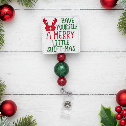 Christmas-themed badge holder with decorative beads and a card on a white wooden background.