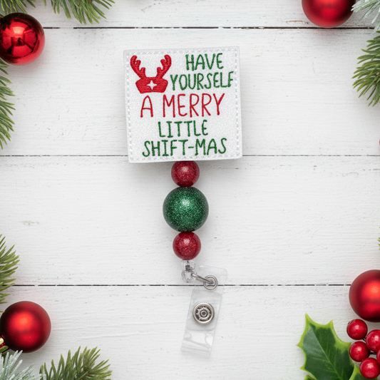 Christmas-themed badge holder with decorative beads and a card on a white wooden background.