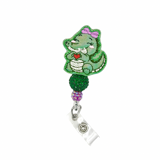 Green dinosaur-shaped badge holder with a heart on a white background