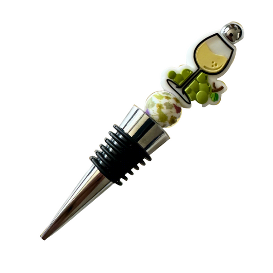 Wine bottle stopper with a decorative top featuring a wine glass and grapes on a beige background