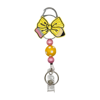 Keychain with yellow bow, pink and yellow beads, and a clear bottle holder on a white background