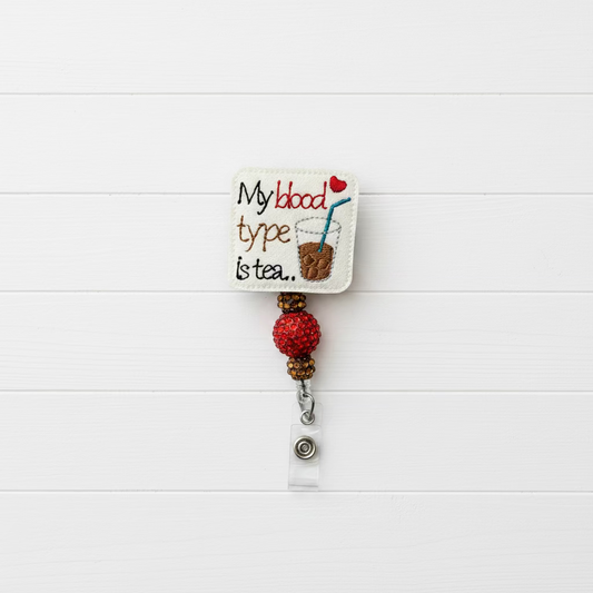 An embroidered badge reel featuring a white square patch with the text 'My blood type is tea.