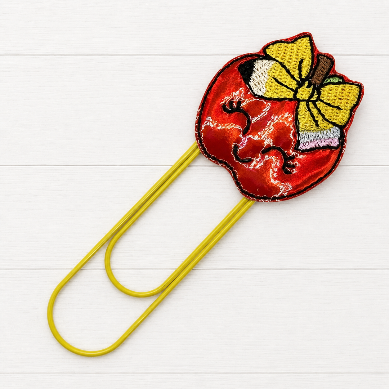 Apple with Bow Oversized Paperclip on a clean white wood background