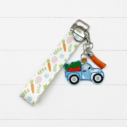 Blue Truck with Carrots Keychain and Wristlet on clean white painted wood background