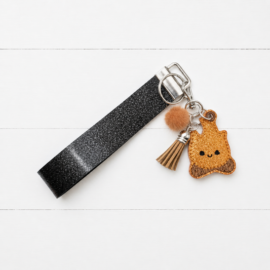 Camp Fire Keychain and Wristlet on clean white painted wood background