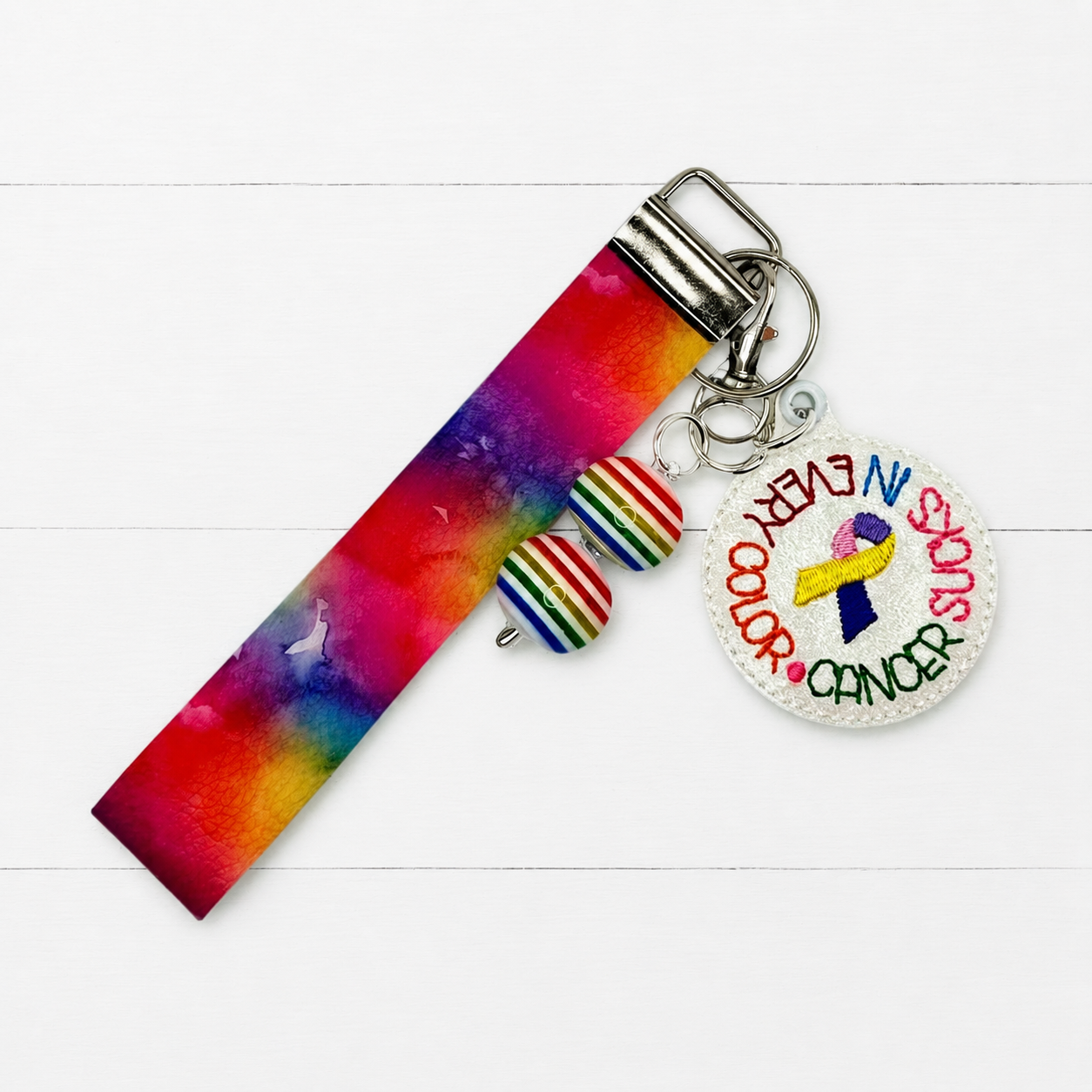 Cancer Sucks Keychain and Wristlet on clean white painted wood background