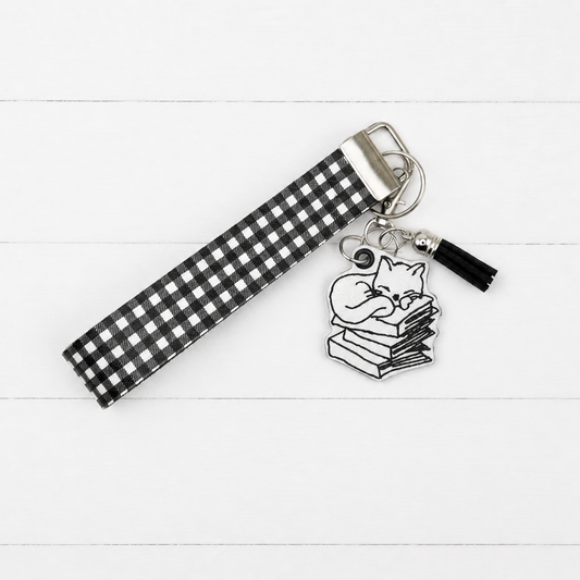 Cat on Books Keychain and Wristlet on clean white painted wood background