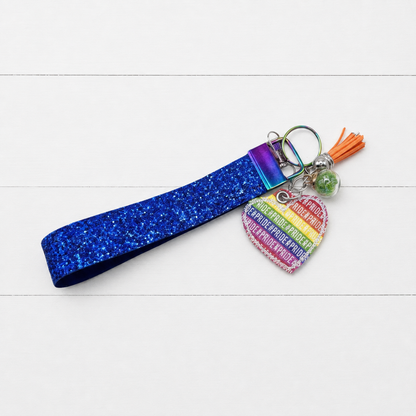 Pride Heart Keychain and Wristlet on clean white wood background