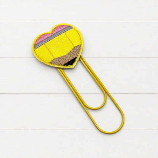 Pencil Oversized Paper Clip on a clean white wood background