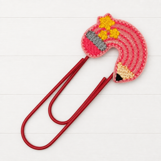 Pencil Rainbow oversized paperclip on a clean white wood background