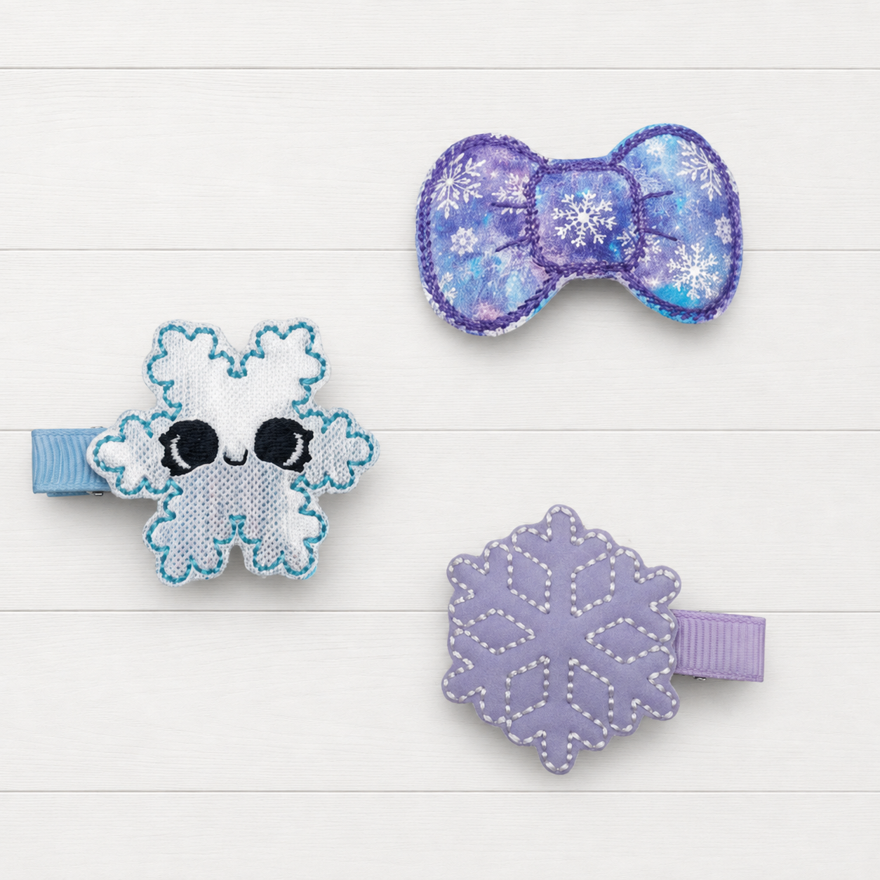 Purple and blue snowflake hair clip set on a clean white wood background