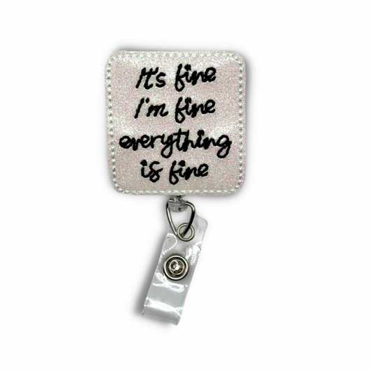 A felt badge reel with a white background and black text that reads "It’s fine, I'm fine, Everything is fine". The badge reel features a clip on the back and a clear vinyl strap to hold an ID or badge.
